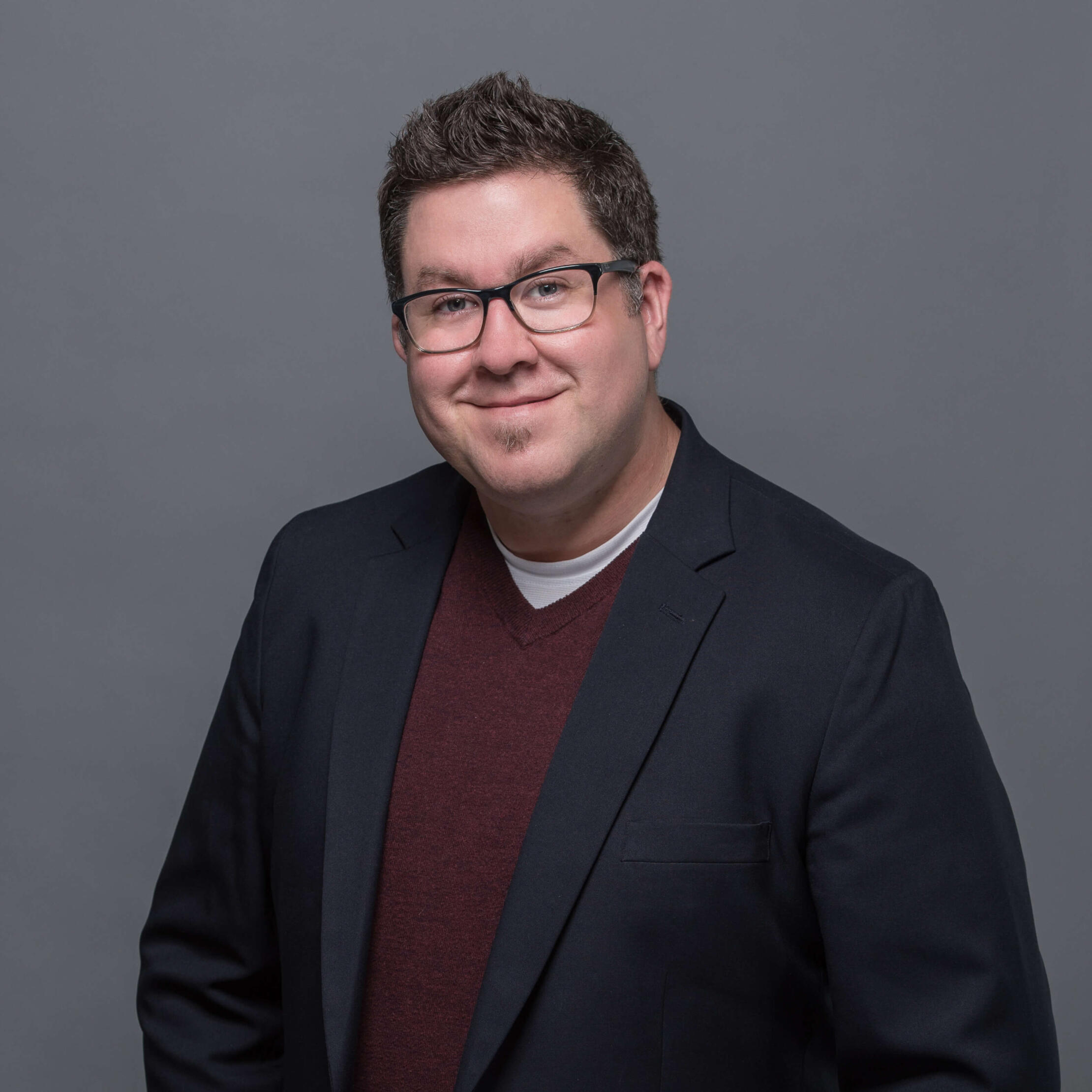 headshot of Jared Wade wearing a red shirt and blue blazer