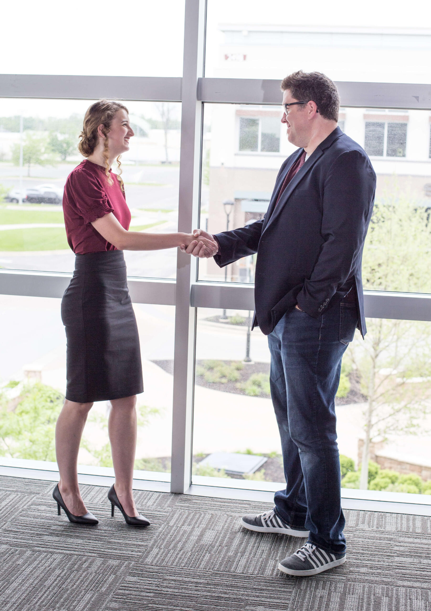 a man and a woman shaking hands smiling at each other.